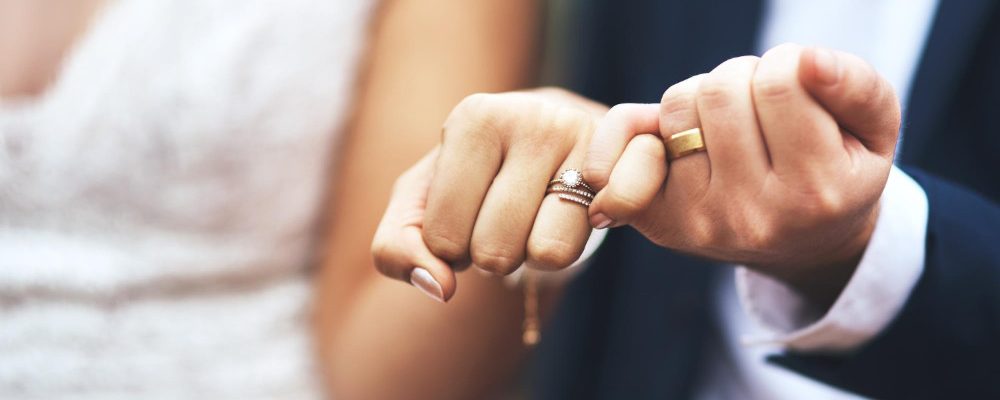 Novios uniendo sus manos con anillos de boda, simbolizando su unión y el inicio de una vida juntos.