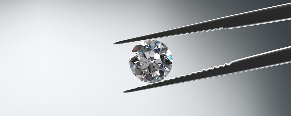 Un diamante brillante sostenida por pinzas de joyero, destacando la precisión en la evaluación de su valor.
