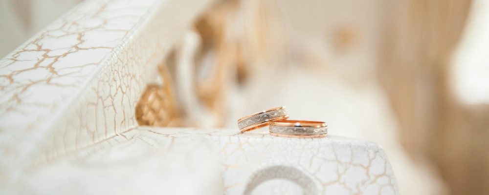 Alianzas de boda en oro y plata reposando delicadamente sobre una superficie texturizada, simbolizando la unión y estilo en el día especial.
