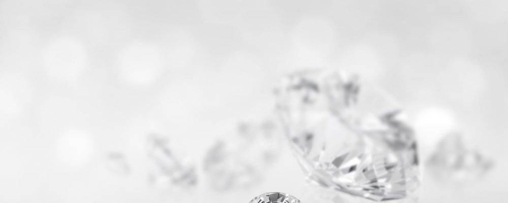 Diamantes brillantes dispersos sobre un fondo luminoso y desenfocado, evocando la pureza y el valor de la inversión en gemas.