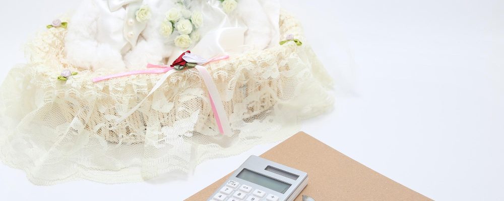 Dos ositos de peluche vestidos de novios, junto a una calculadora, un bolígrafo y una libreta, simbolizando la planificación del presupuesto de una boda.